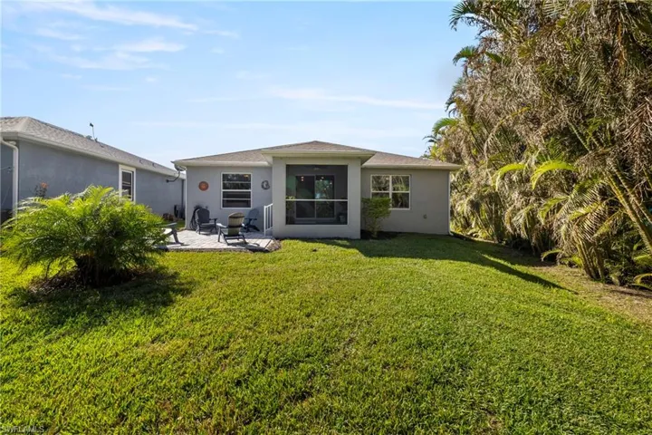 Rear view of property with stucco siding, a patio area, and a yard