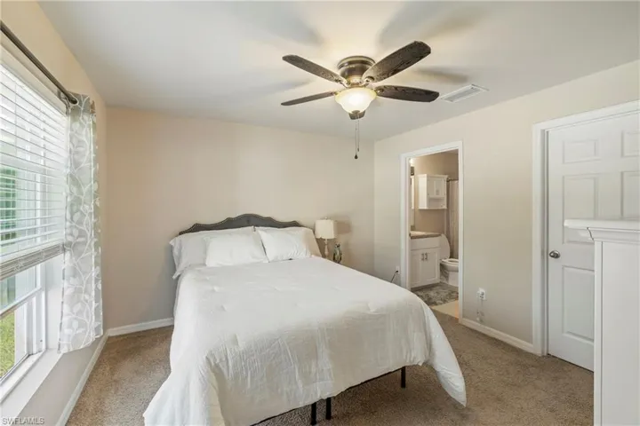 Bedroom featuring light carpet, ceiling fan, and ensuite bathroom