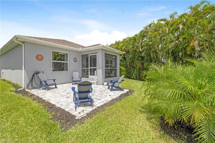 Rear view of house featuring a sunroom, a fire pit, stucco siding, a patio, and a yard