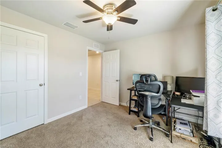 Carpeted office space with baseboards and a ceiling fan