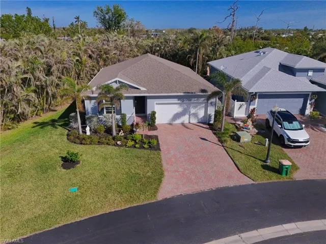 View of front of home with decorative driveway, a front yard, roof with shingles, and a garage