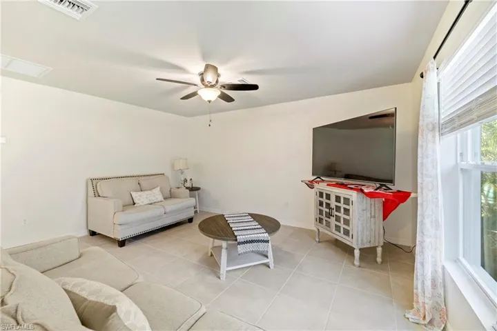 Living area with light tile patterned flooring and ceiling fan