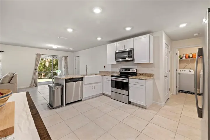 Kitchen featuring light tile patterned floors, white cabinetry, stainless steel appliances, a peninsula, and open floor plan