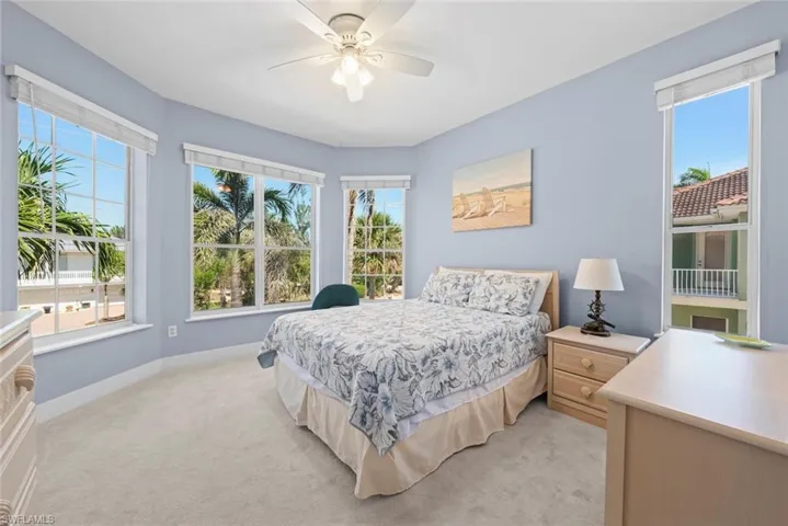 Carpeted room featuring multiple large windows, a ceiling fan, and light blue wall finishes