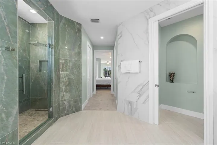Spacious bathroom featuring a glass-enclosed shower with green marble-finish tile, a rainfall showerhead, and a built-in shower niche