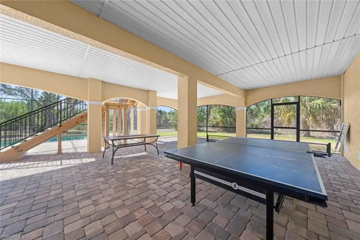 Expansive screened patio featuring a paver flooring, a white slatted ceiling, and arched openings