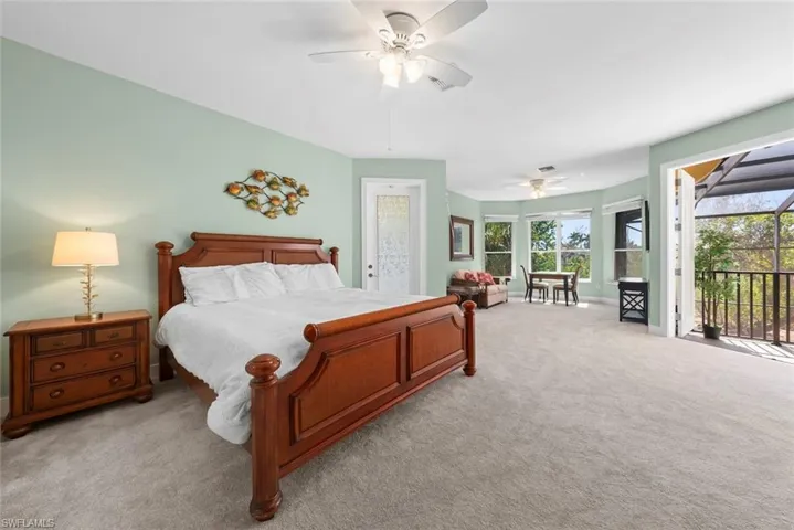 Spacious carpeted room featuring a ceiling fan, a private screened balcony, and a bay window area