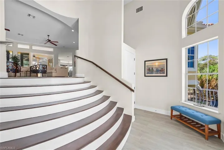 Grand curved staircase with dark wood-finish treads and white risers