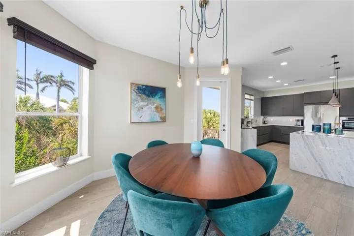 Dining area featuring wood-finish flooring, a contemporary chandelier, and ample natural light