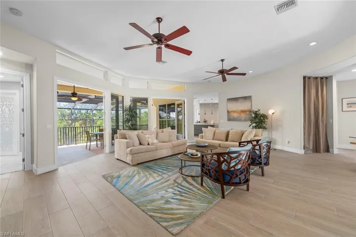 Spacious living area featuring wood-finish flooring, two ceiling fans, and an expansive screened-in patio