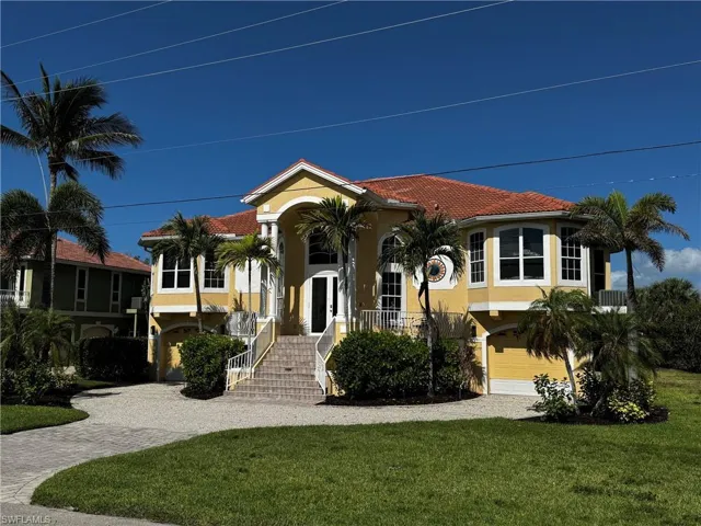 Mediterranean-style residence featuring a terracotta tile roof and light yellow stucco exterior