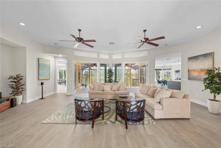 Expansive living area featuring light wood-finish flooring, recessed lighting, and two ceiling fans