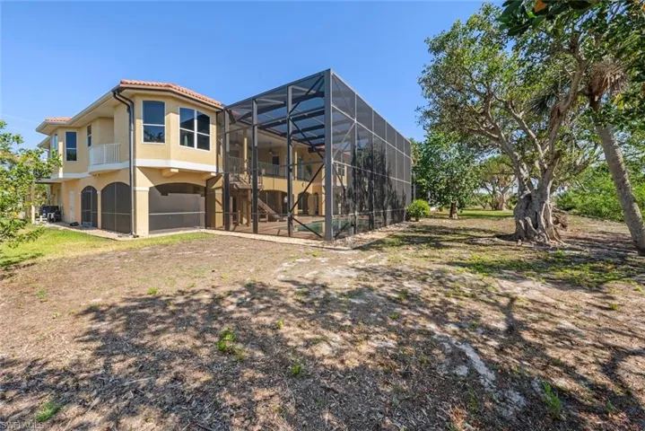 Two-story residence featuring a terracotta tile roof, stucco exterior, multiple arched screened entries, and a screened swimming pool enclosure