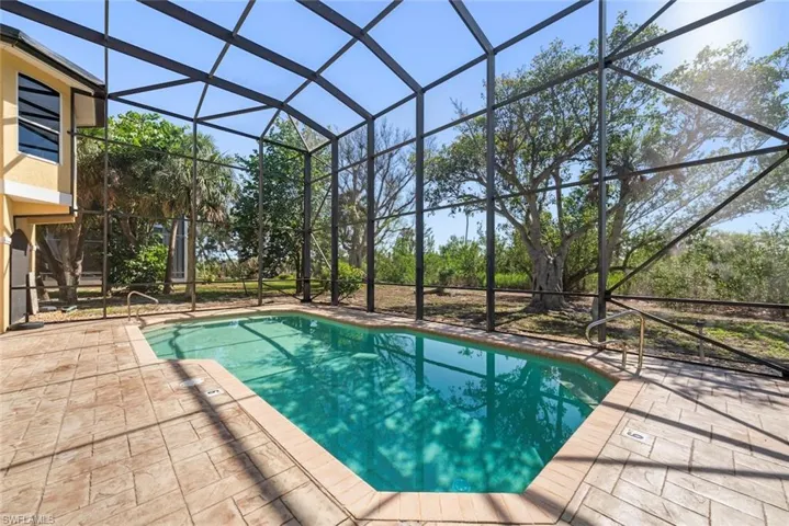 Screened-in swimming pool with a tan stamped concrete deck and integrated pool steps