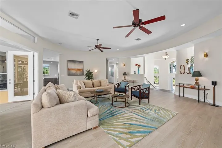 Spacious living area featuring light wood-finish flooring, recessed lighting, and multiple ceiling fans