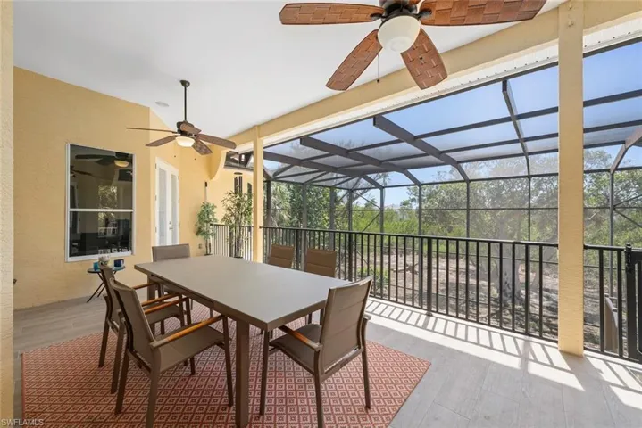Spacious screened lanai featuring wood-finish flooring, two ceiling fans, and a white framed window