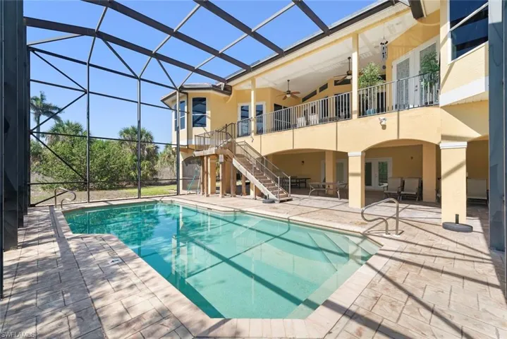 Screened lanai featuring a swimming pool, extensive patio, and a covered ground-level entertainment area