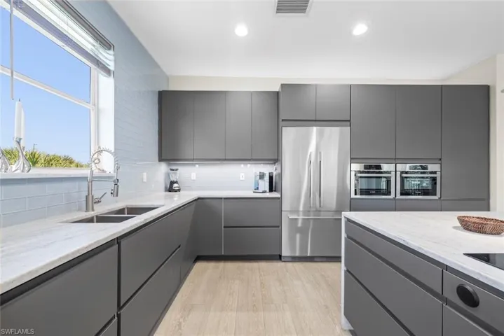 Contemporary kitchen featuring sleek gray cabinetry, light-toned wood-finish flooring, and a light-colored countertop