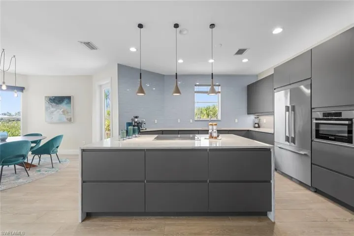Kitchen featuring a central island with integrated storage, light-toned countertop, and three pendant lights