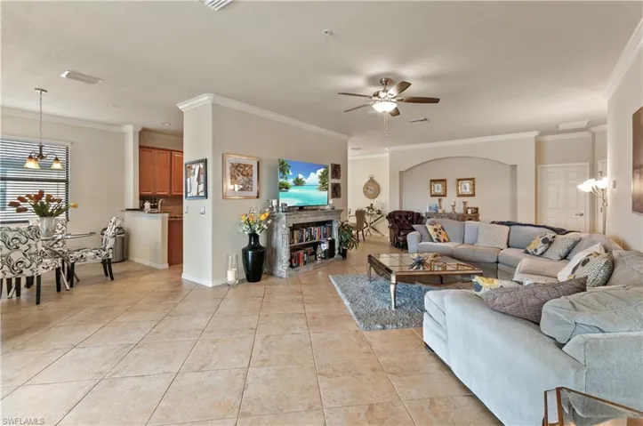 Living room with ornamental molding, light tile patterned floors, and ceiling fan