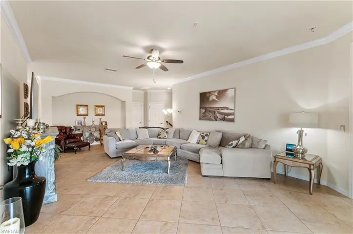 Living room with crown molding, ceiling fan, and light tile patterned floors