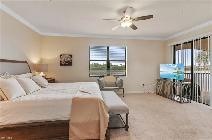 Carpeted bedroom with multiple windows, crown molding, and ceiling fan