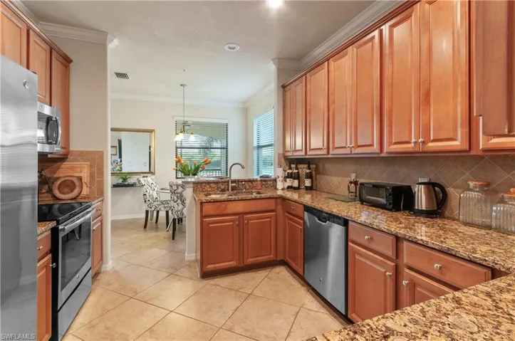 Kitchen featuring pendant lighting, crown molding, stainless steel appliances, and decorative backsplash