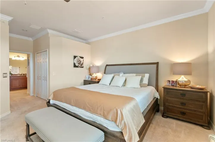 Bedroom with ensuite bath, ornamental molding, a closet, and light carpet