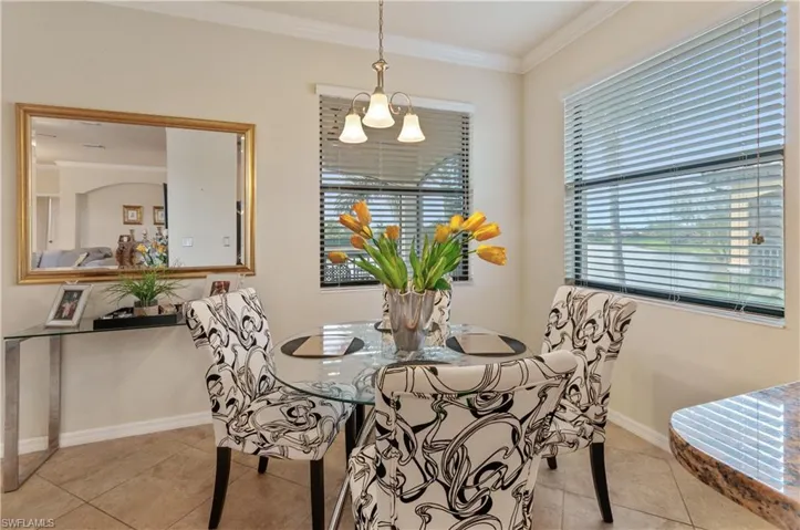 Tiled dining space with crown molding and a chandelier