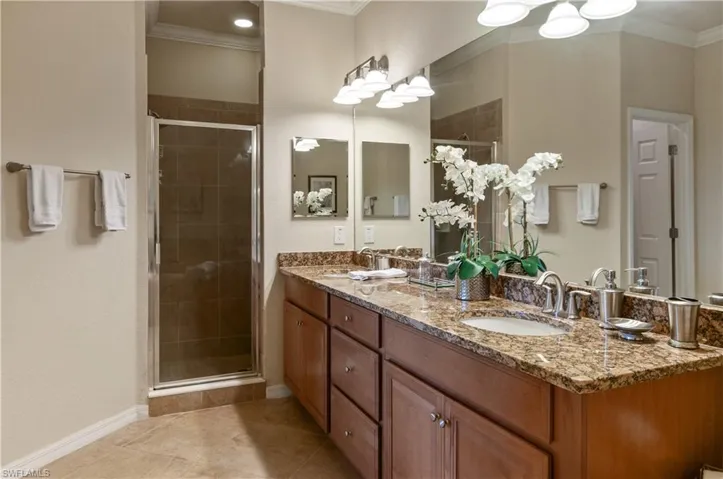 Bathroom with an enclosed shower, ornamental molding, and tile patterned floors