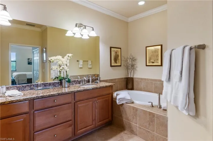 Bathroom with vanity, tiled tub, tile patterned floors, and ornamental molding