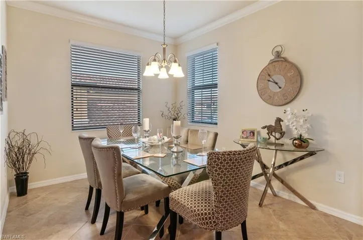 Tiled dining room with ornamental molding and a notable chandelier