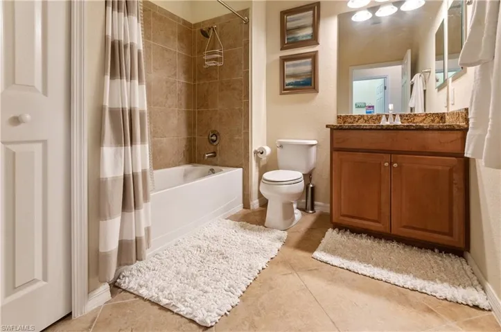 Full bathroom featuring shower / tub combo with curtain, vanity, toilet, and tile patterned floors