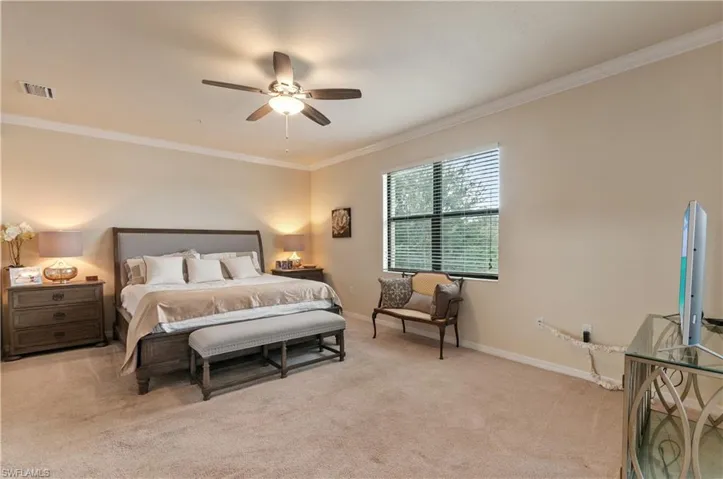 Bedroom featuring ceiling fan, light colored carpet, and ornamental molding