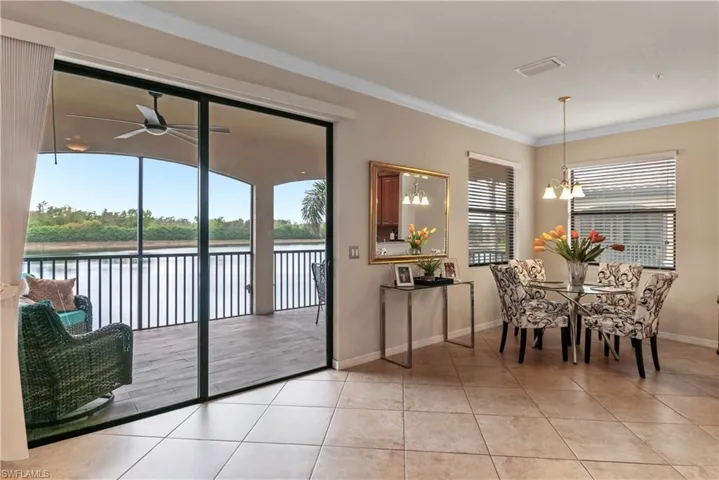 Tiled dining space with ornamental molding, a water view, a wealth of natural light, and ceiling fan with notable chandelier