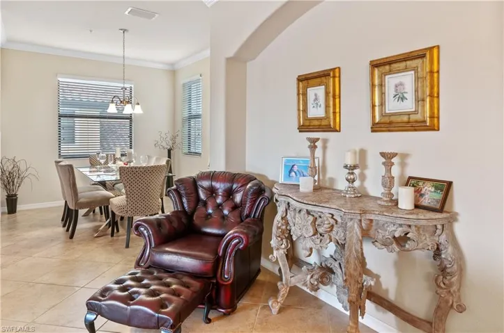 Living area featuring crown molding, light tile patterned floors, and a chandelier