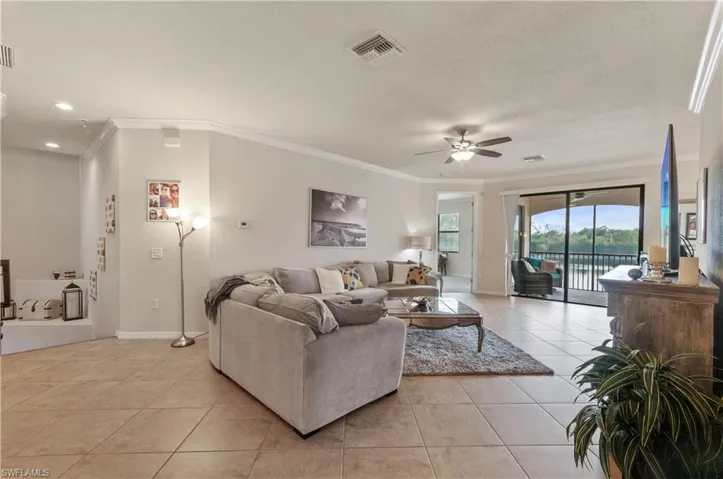 Tiled living room featuring ceiling fan and ornamental molding