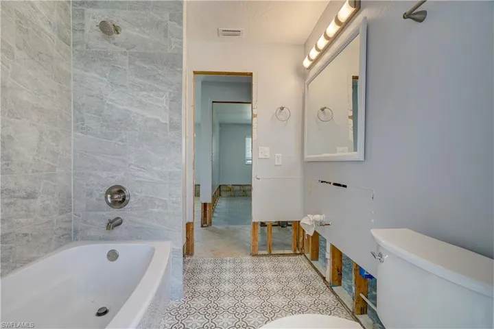 Bathroom with tile patterned flooring, tiled shower / bath combo, and toilet