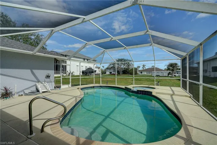View of swimming pool with a lawn, glass enclosure, and a patio
