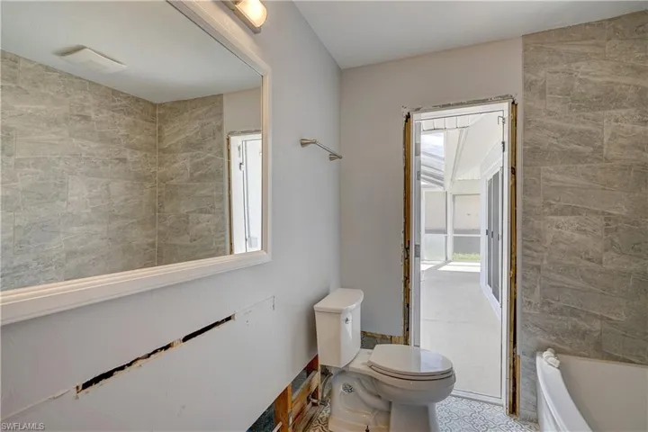 Bathroom featuring a washtub and toilet