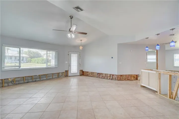 Living room featuring ceiling fan, light tile patterned floors, and vaulted ceiling
