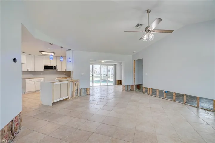 Unfurnished living room with ceiling fan, light tile patterned flooring, and vaulted ceiling
