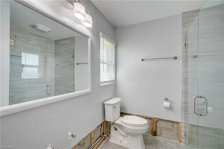 Primary bathroom with wood-style tile floors, and enclosed shower, and toilet