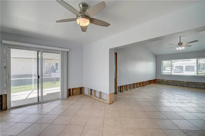 Den featuring ceiling fan, light tile patterned floors, and lofted ceiling