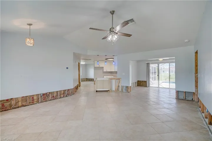 Unfurnished living room with lofted ceiling, ceiling fan, and light tile patterned floors