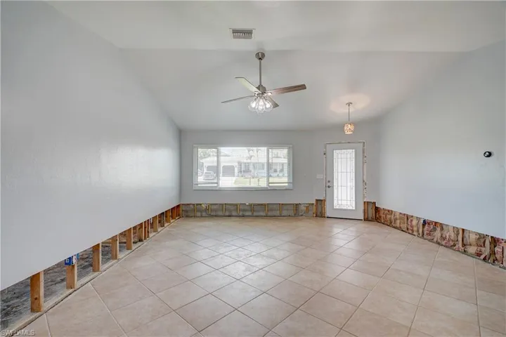 Living room with ceiling fan, light tile patterned floors, and vaulted ceiling