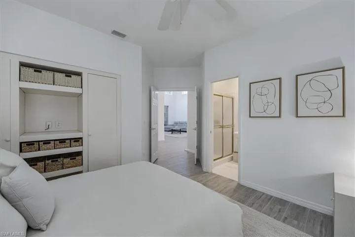 Bedroom with light wood-type flooring, ceiling fan, and ensuite bathroom