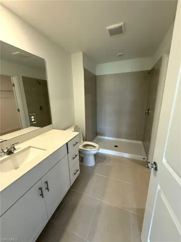 Full bathroom with vanity, tile patterned floors, and a tile shower