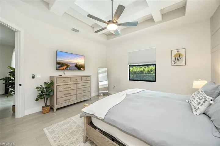 Tray ceiling with a modern ceiling fan, light wood-finish flooring, and a large window