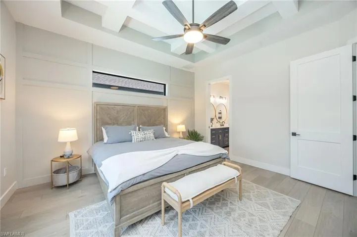 Coffered ceiling with a modern ceiling fan, plank flooring, and a decorative accent wall with a horizontal transom window